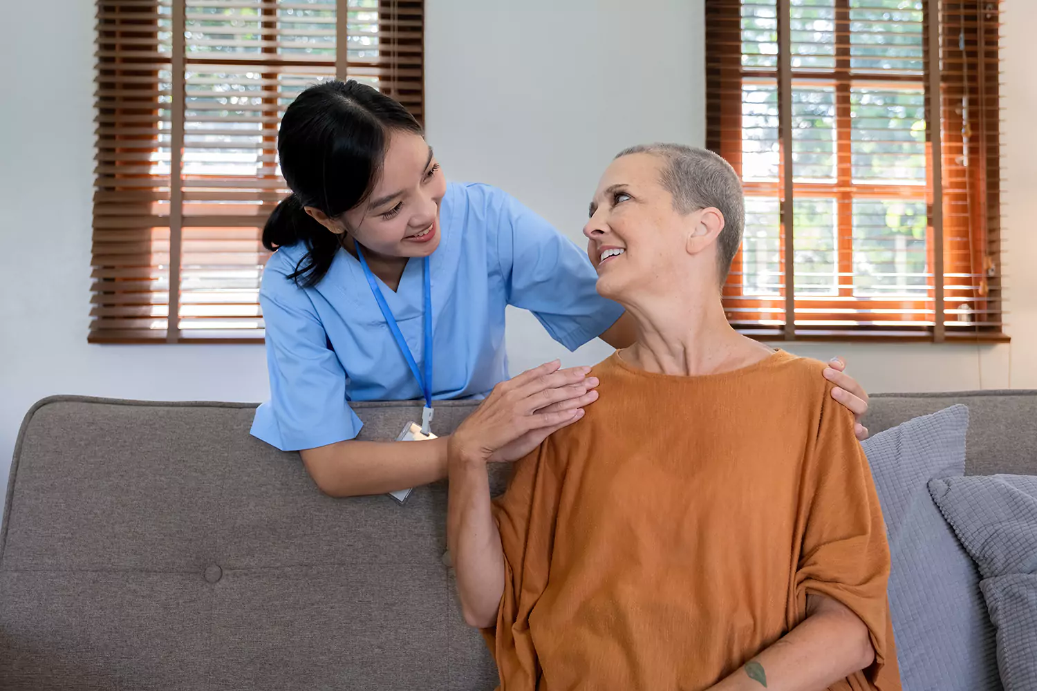 Woman sitting on couch looking back and smiling at nurse