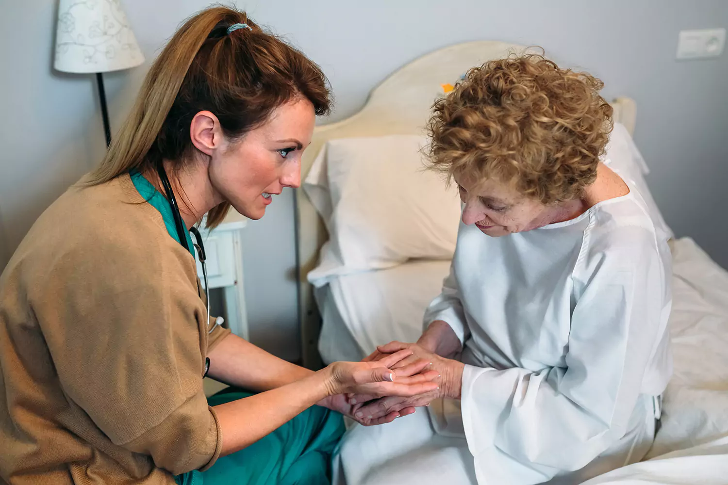 Nurse holding elderly woman's hands