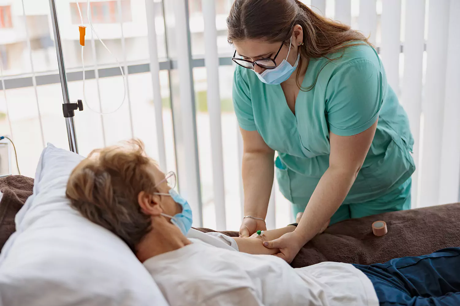 Nurse inserting drip into elderly patient