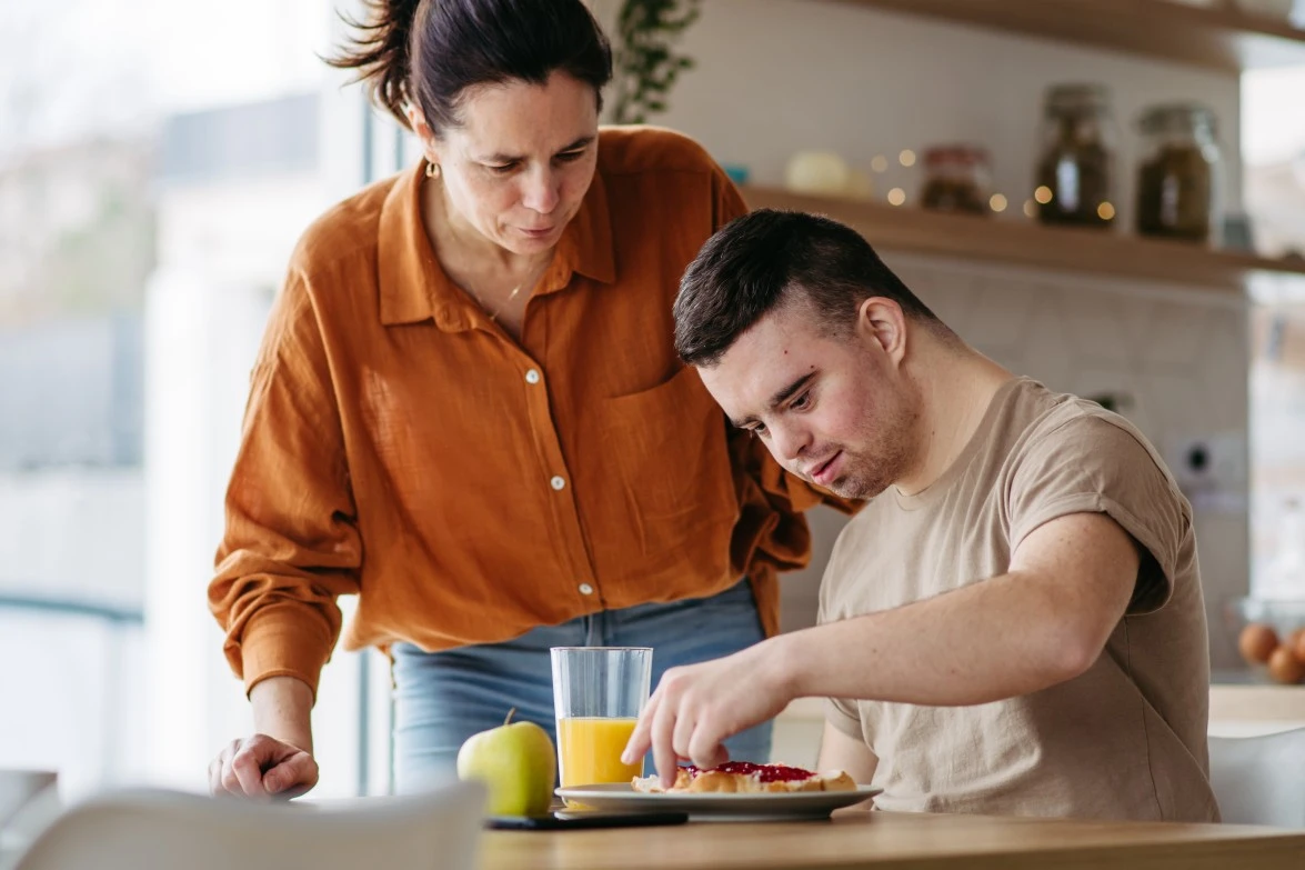 Disabled man with down syndrome making breakfast at home with support worker
