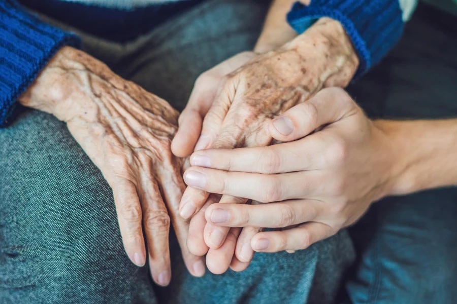 Close up of elderly hands holding younger persons hands